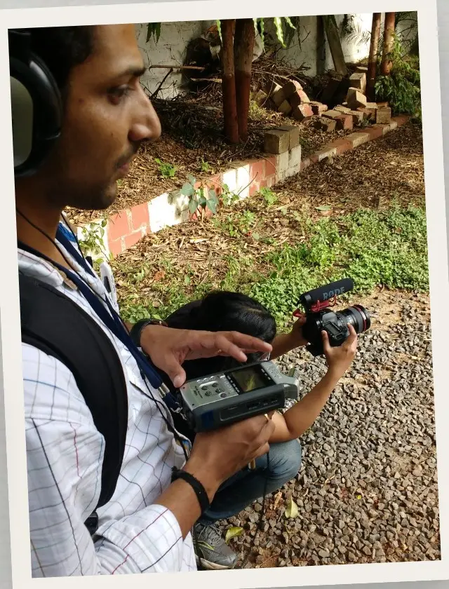 Sound recordist monitoring a field recorder