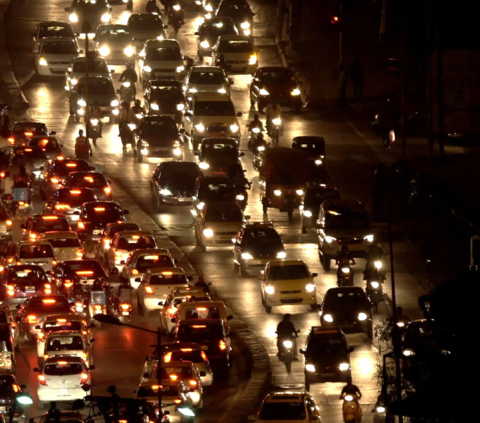 Rows of car headlights jammed on a city road at night
