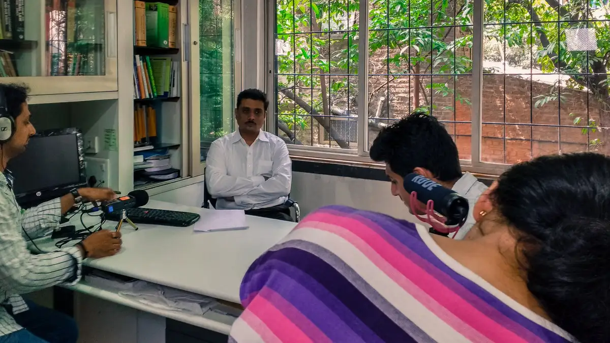 Seated interview in a garden, crew with camera