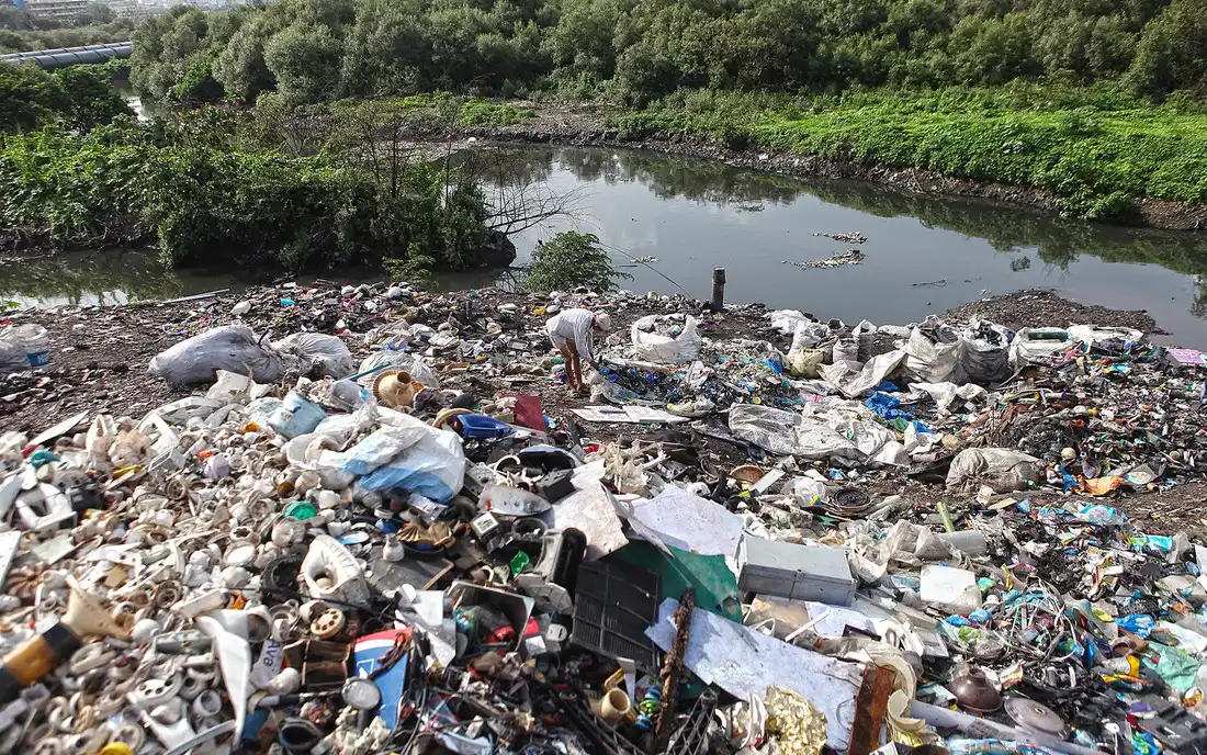 Plastic and household waste piled on the bank of an urban stream